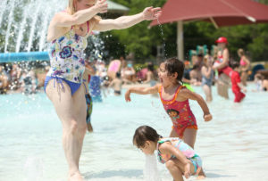 Jennifer Ronquillo, of Madison, plays with her daughters, Sienna, 3, and Neaveh, 1, at bottom, at Goodman Pool on opening day, Friday, Madison's first 90-degree day of the year.