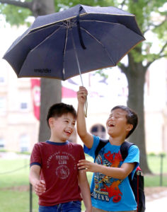 Chavez Elementary School students Josh Gonzales, left, and Dorgee Tsering enjoy a rain shower during a trip to the UW-Madison campus in May. Spring showers gave way to a rainy summer for southern Wisconsin. (Photo credit: John Hart, State Journal archives)